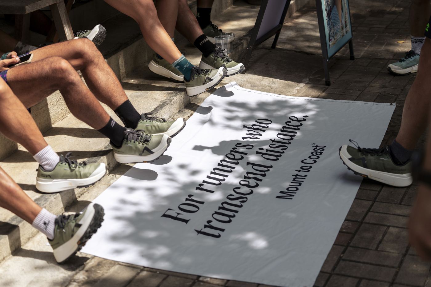 Mount to Coast M1 challenge, runners' shoes around a brand banner
