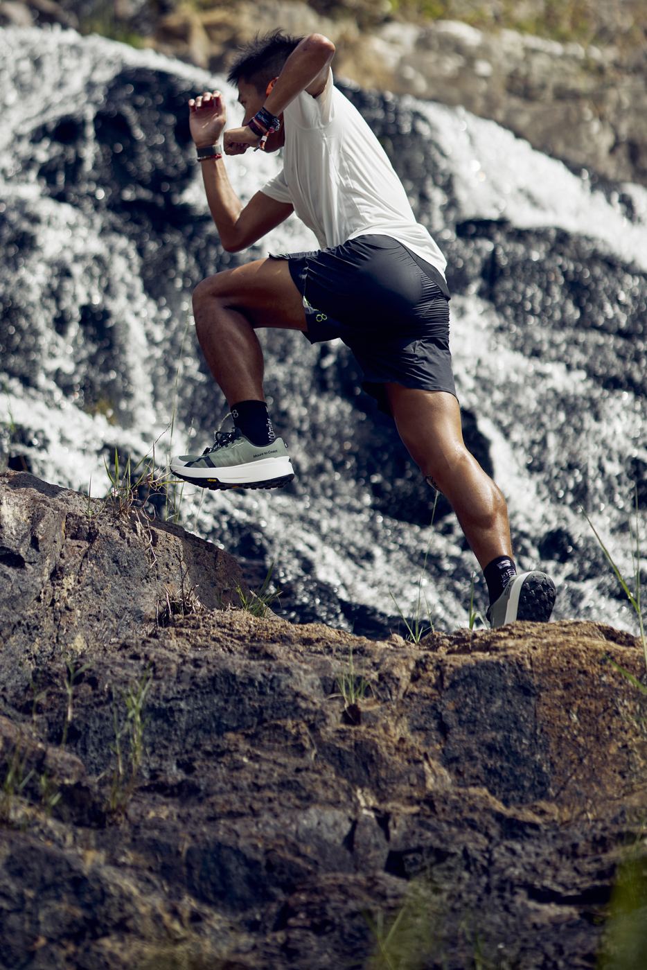 Mount to Coast athlete leaping up rocks in front of a waterfall