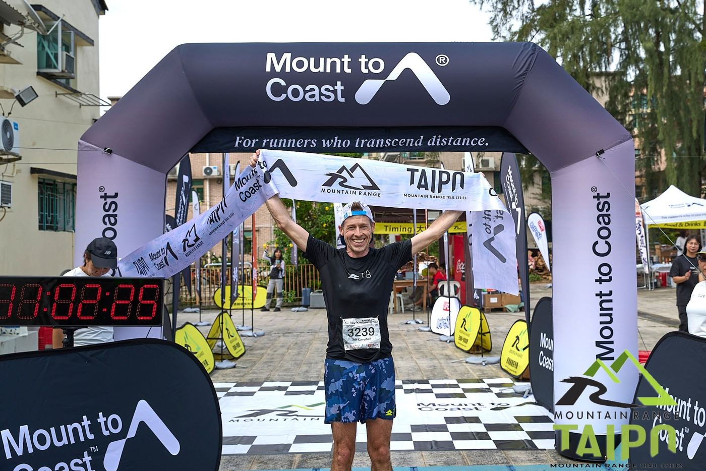 Runner celebrating at the Mount to Coast finish arch