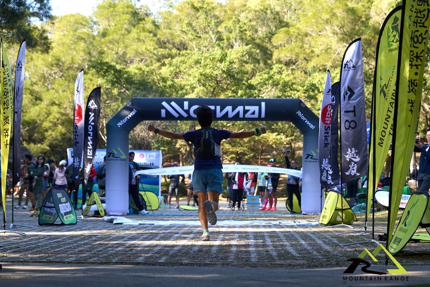 Runner crossing the NNormal finish arch at a Mountain Range trail race