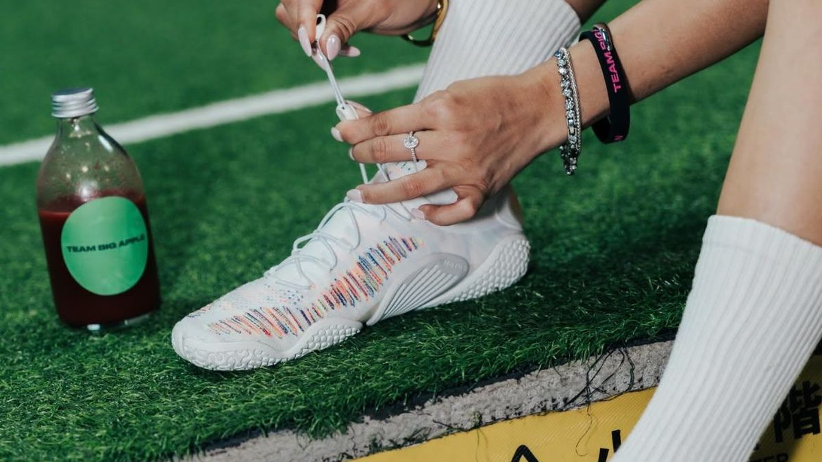 Lacing up Vivobarefoot shoes on an indoor turf track